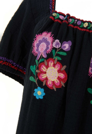 close-up-of-a-black-embroidered-blouse-featuring-vibrant-floral-patterns-in-pink-purple-blue-and-green-with-red-and-purple-trim-along-the-neckline