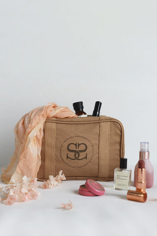 An image of the Spell Curators Club Cosmetic Bag surrounded by cosmetics and the Sloan Travel Scarf.